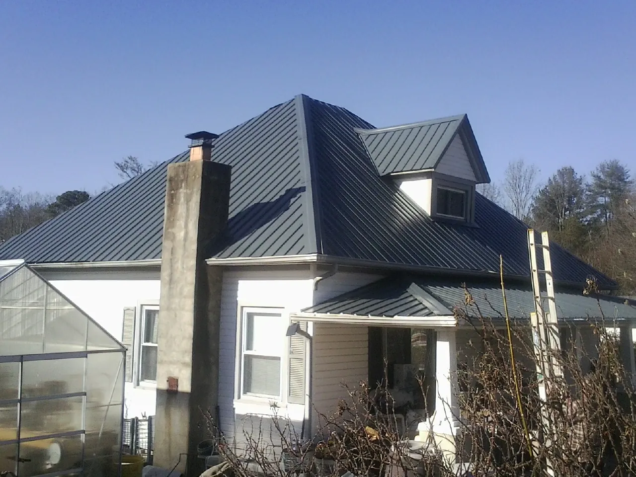 Dark blue standing seam metal roof on a white farmhouse with dormer — Slate & Tile Roof Repair by Roofing Brothers in Upper Black Eddy