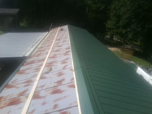 Old rusted panels beside newly installed green metal roofing — Wind Damage Roof Repair by Roofing Brothers in Upper Black Eddy