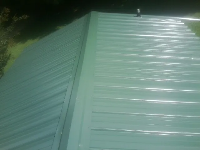 New green metal panels meeting at the ridge of a roof — Flat Roof Repair work by our crew in Upper Black Eddy