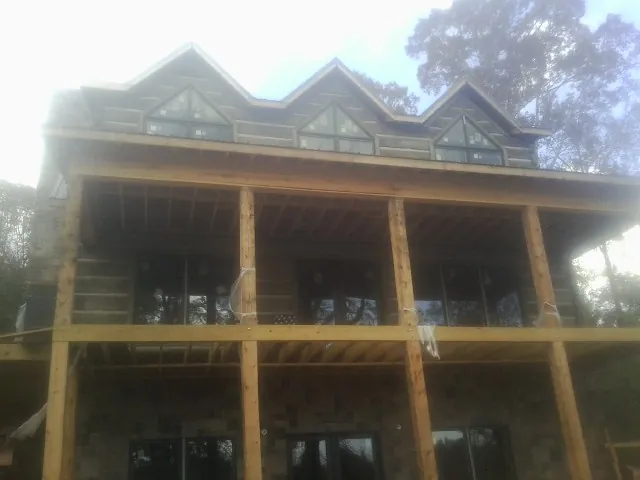 Dormers and porch framing on a large log home under construction — Roof Coating work by our crew in Upper Black Eddy