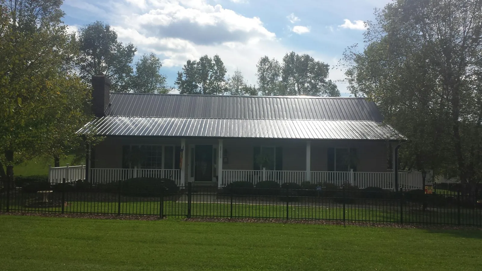 Gray metal roof on a brick ranch with a full width front porch — Gutter Guard Installation work by our crew in Upper Black Eddy