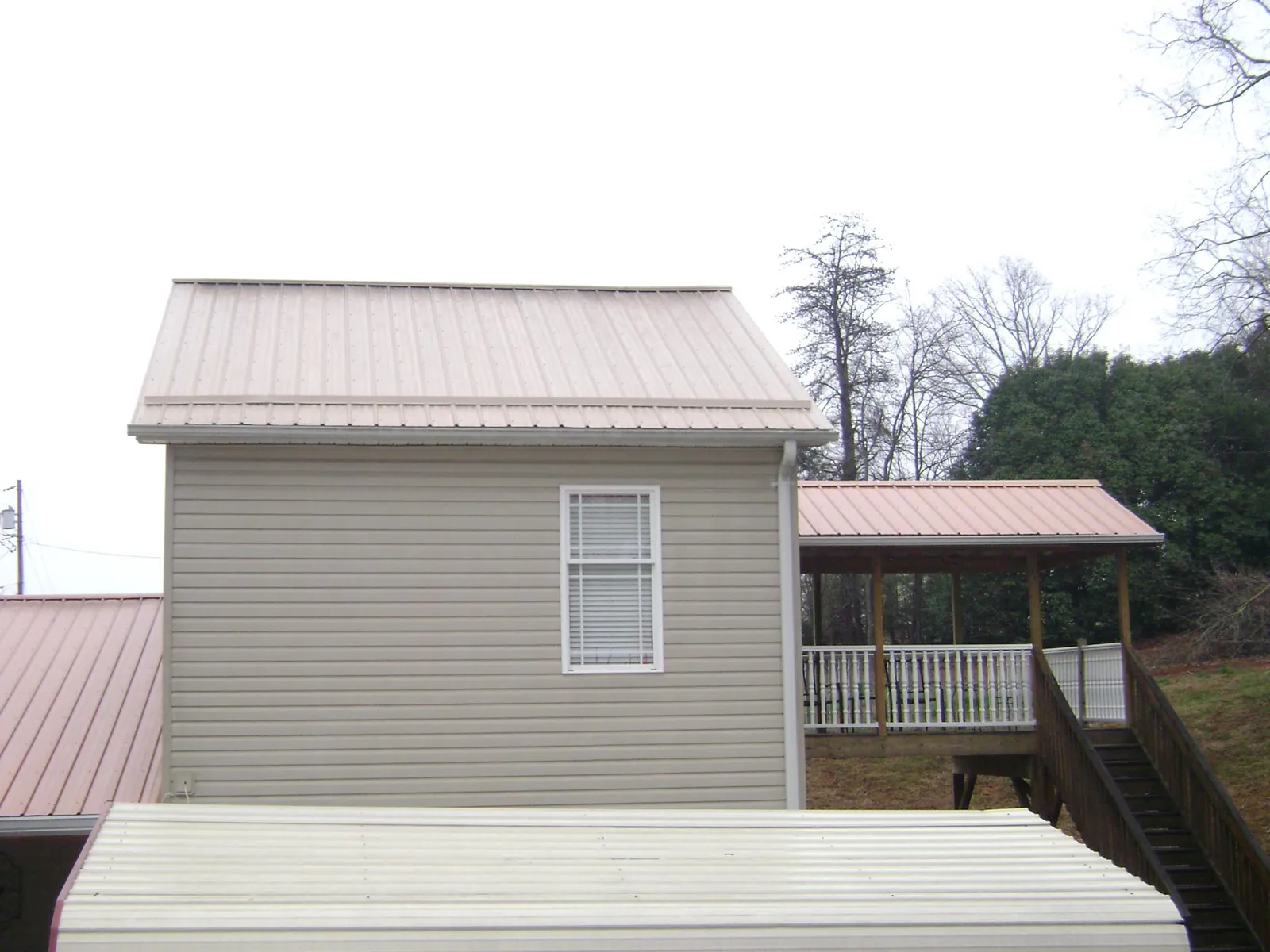 Tan metal roofs on a two story addition and attached porch, from a Roof Replacement job in Upper Black Eddy