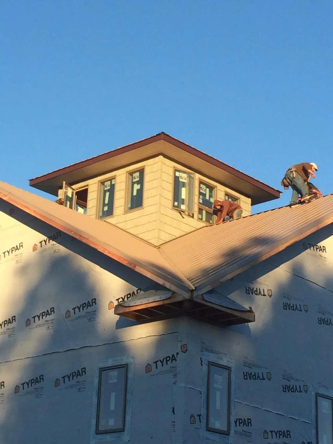 Roofers working around a rooftop cupola on a new metal roof at sunset — Roof Waterproofing in Upper Black Eddy by Roofing Brothers